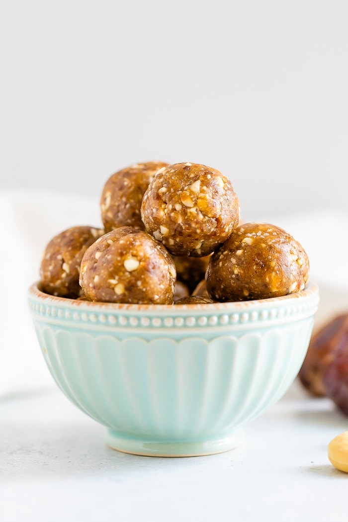 Cashew date balls in a light blue bowl.