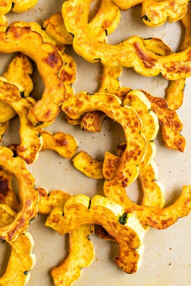 Half moon shapes of roasted delicata squash on a sheet pan.