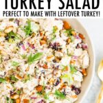 Bowl of creamy turkey salad with celery, cranberries and almonds.