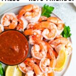 Plate of shrimp cocktail and cocktail sauce. Garnished with parsley and lemon.