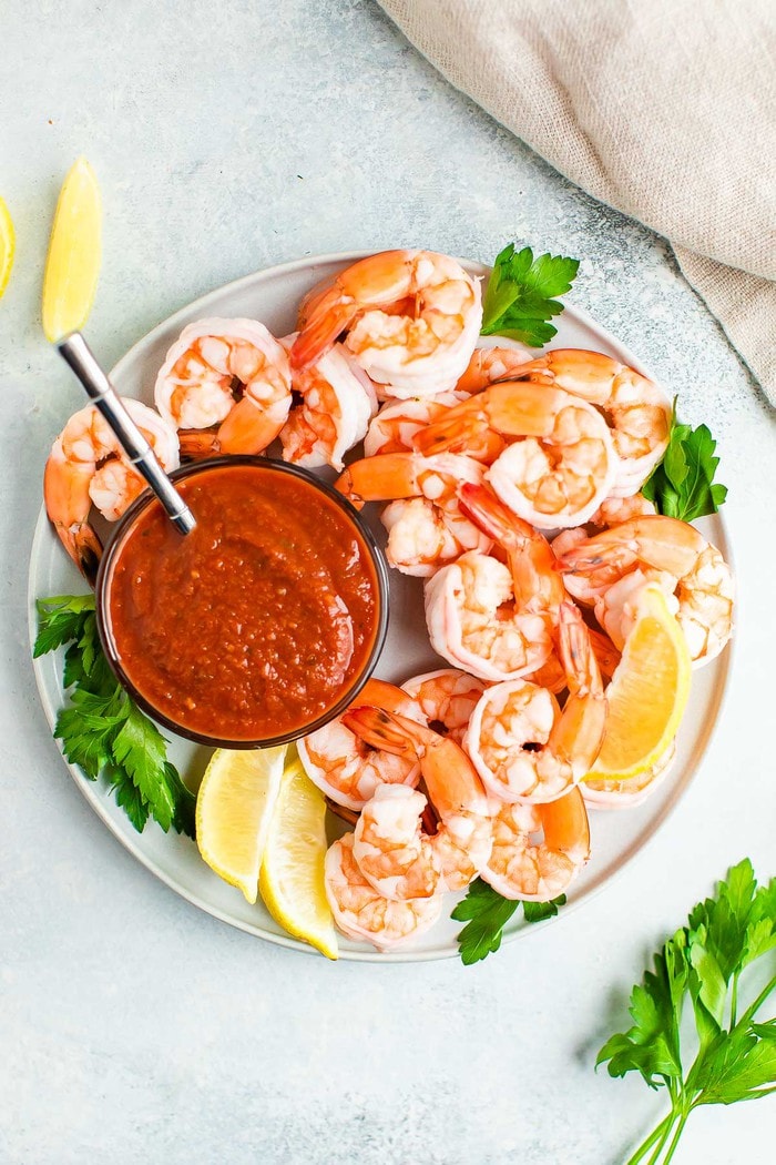 Plate with shrimp cocktail garnished with parsley and lemon.