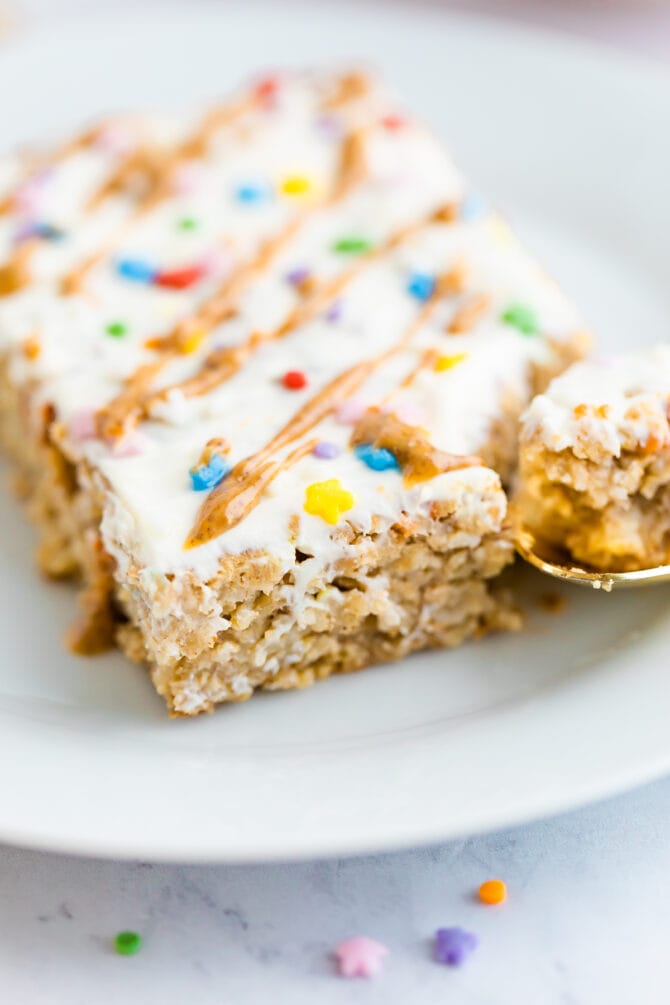A slice of birthday cake baked oatmeal topped with frosting, nut butter drizzle and sprinkles.