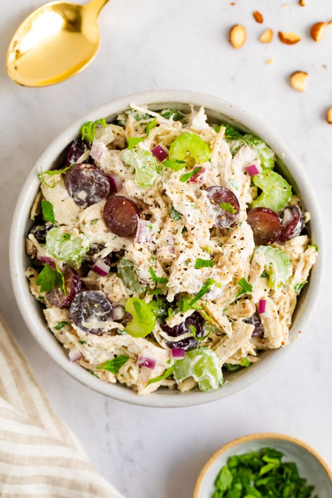 A large serving bowl of yogurt chicken salad with grapes and celery.