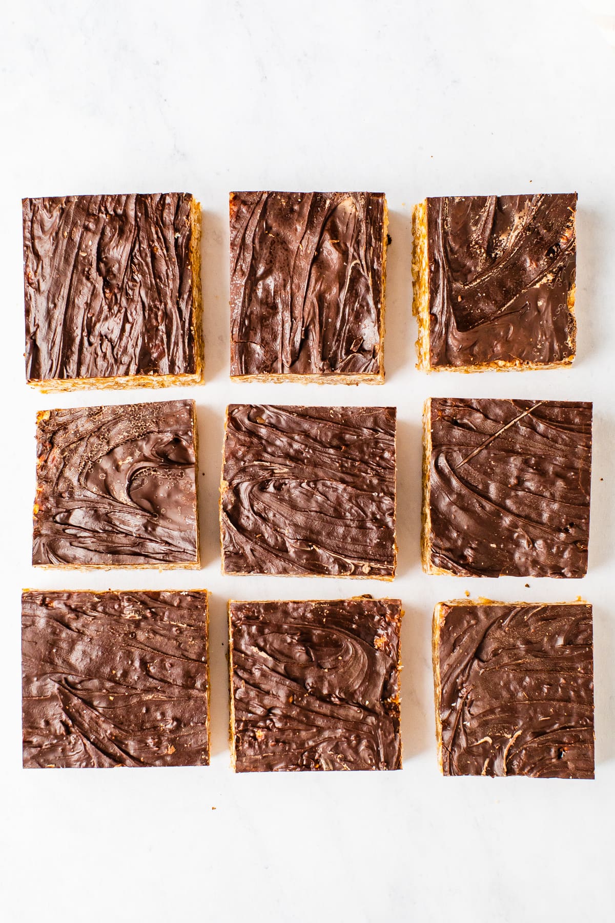9 squares of rice krispie treats topped with chocolate.
