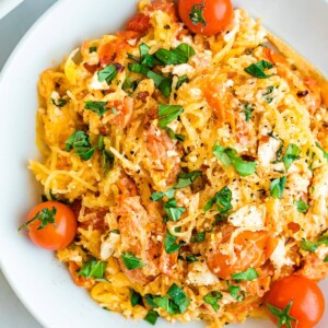 A plate of spaghetti squash with feta, basil and tomatoes.