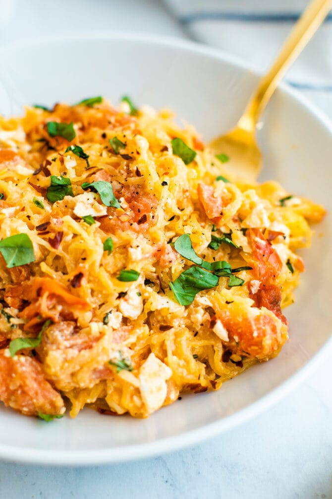 A serving of spaghetti squash with feta, basil and tomatoes in a large bowl.