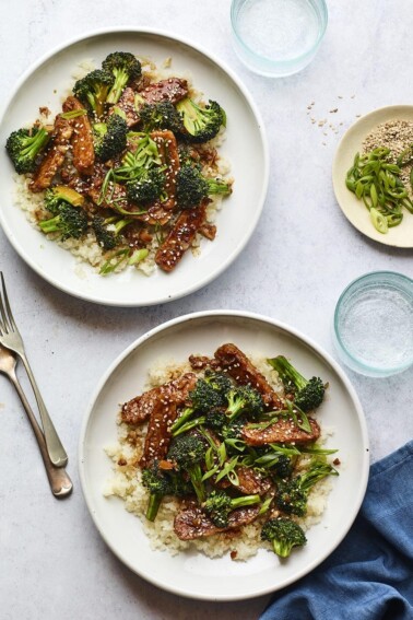 Two plates of teriyaki tempeh and broccoli served over rice.