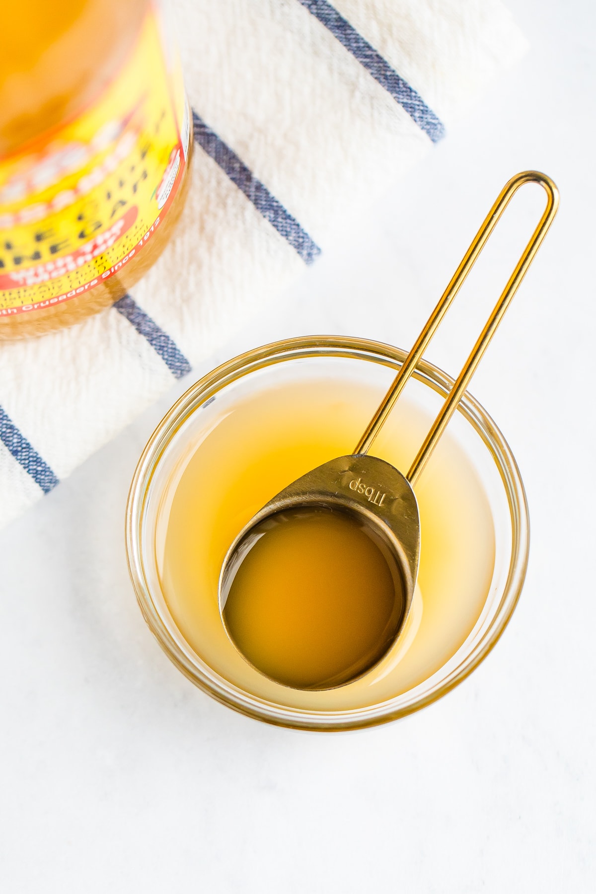 ACV in a tablespoon over a glass cup.