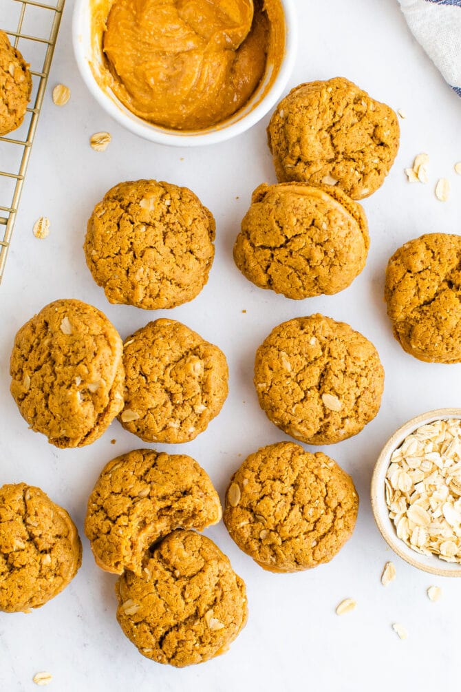 Do si do cookies on a table next to a bowl of peanut butter and oats.