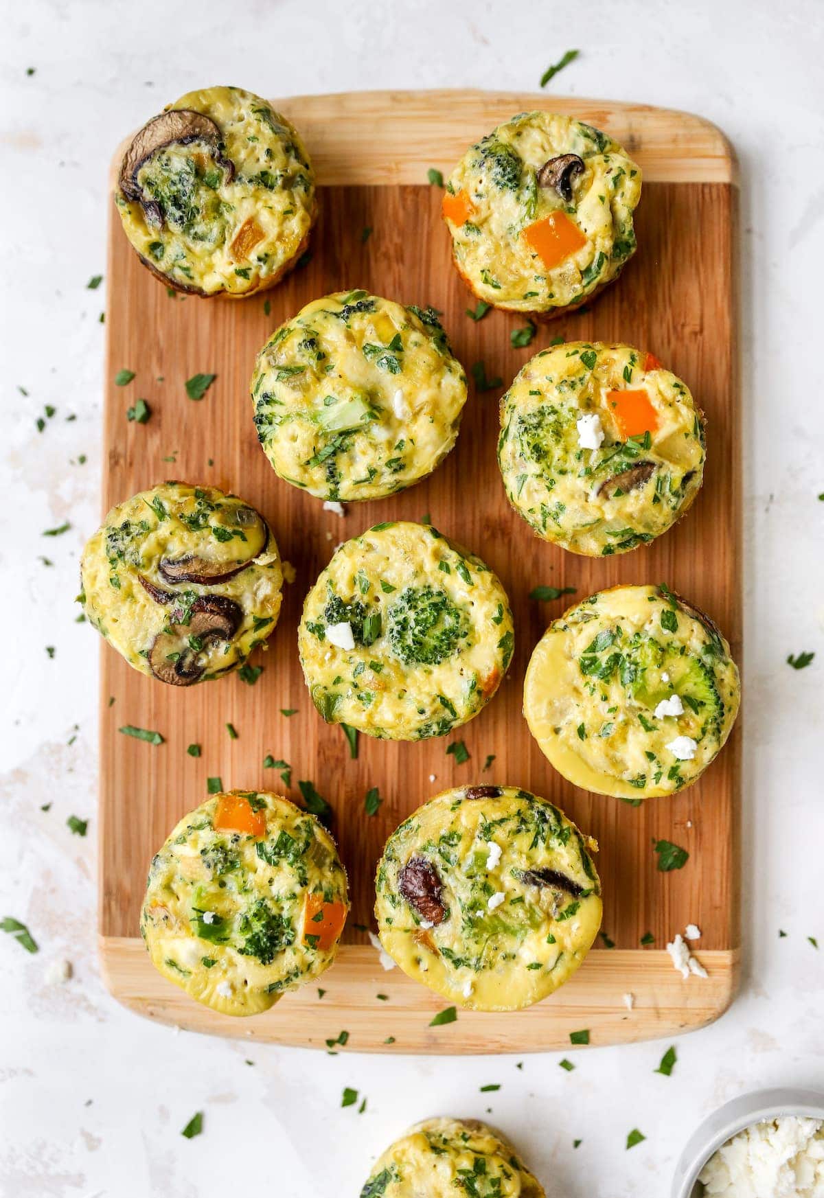 Baked egg and veggie cups on a wood cutting board.
