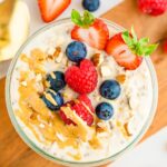 A jar of protein overnight oats topped with berries, almonds and peanut butter.
