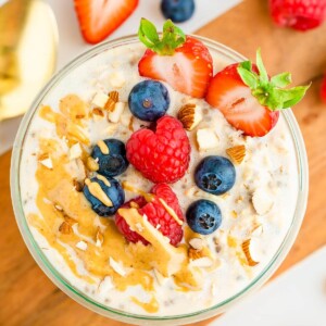 A jar of protein overnight oats topped with berries, almonds and peanut butter.