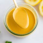 Spoon with tahini dressing from a jar.