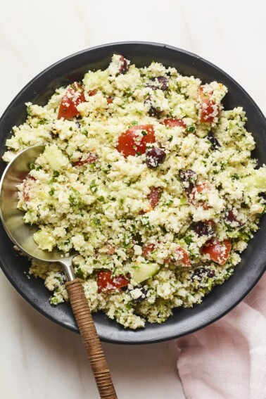 Serving bowl of cauliflower tabbouleh with a serving spoon.