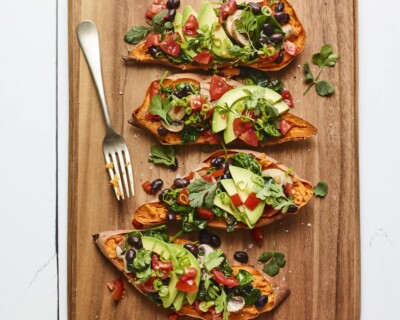 Four black bean stuffed sweet potatoes on a wood cutting board.