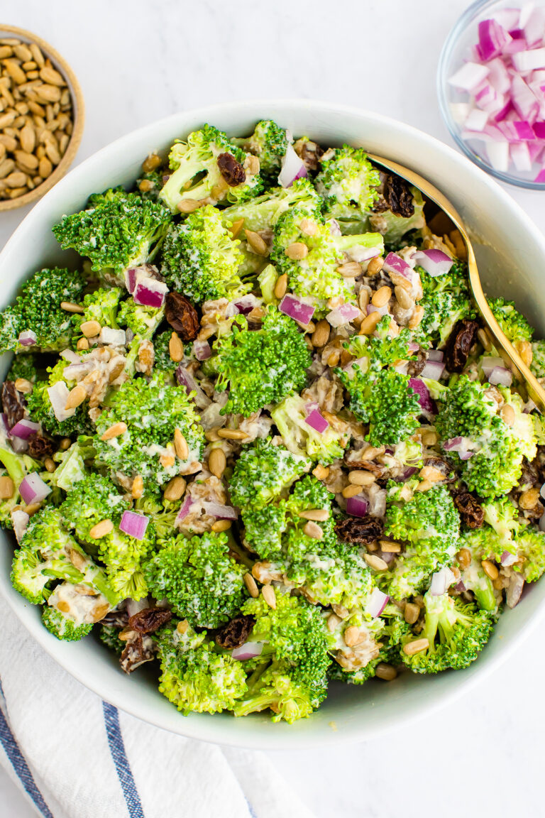 Overhead close up of vegan broccoli salad in a white bowl.