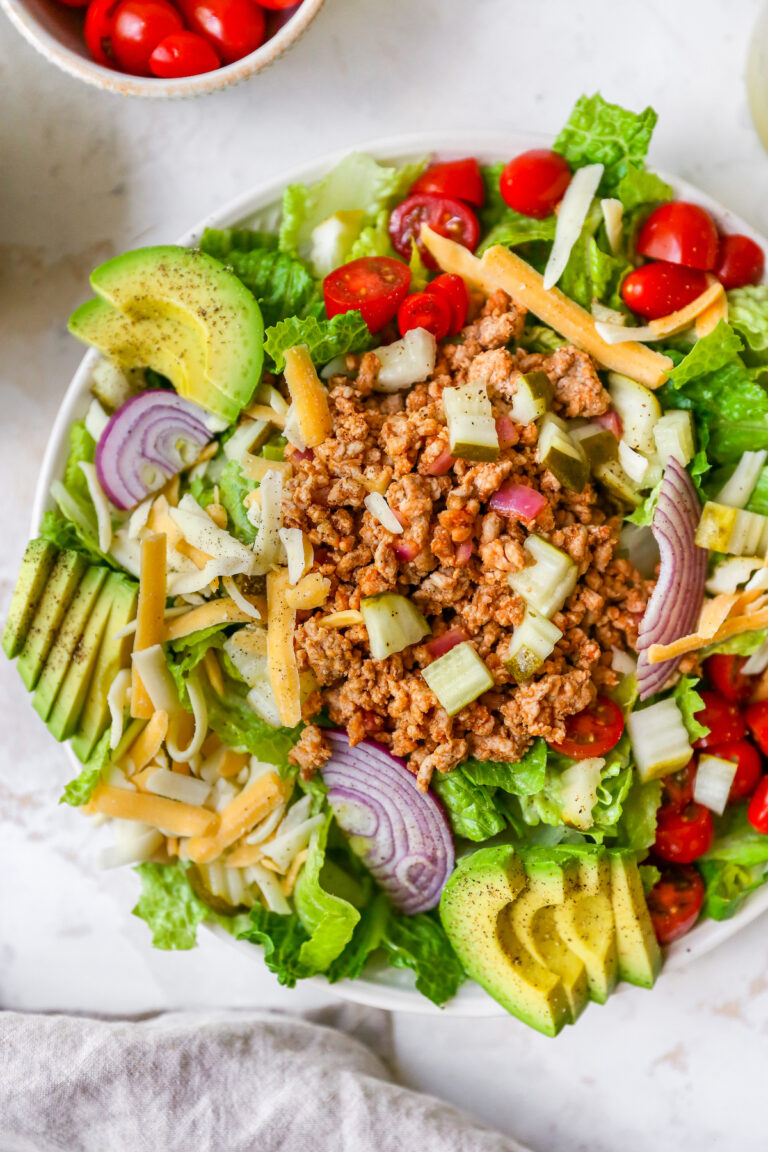 Cheeseburger salad with avocado, red onion, cheddar cheese, tomatoes, ground turkey and pickles.