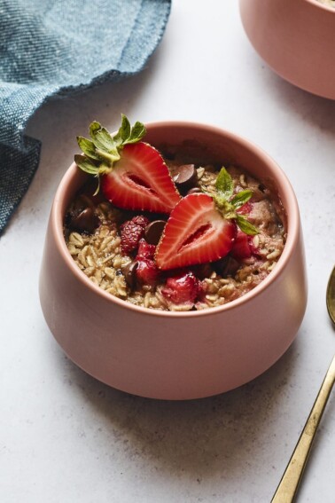 Bowl of strawberry chocolate chip baked oatmeal. A spoon and napkin are next to the bowl.