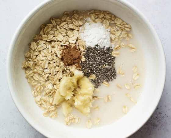 Mixing bowl with oats, almond milk, cinnamon, chia seeds, banana and baking powder.