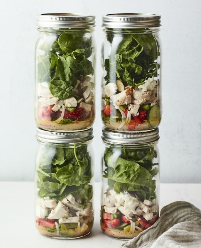 Strawberry Spinach Mason Jar Salad with Citrus Poppyseed Dressing Four mason jars filled with a strawberry spinach chicken salad.