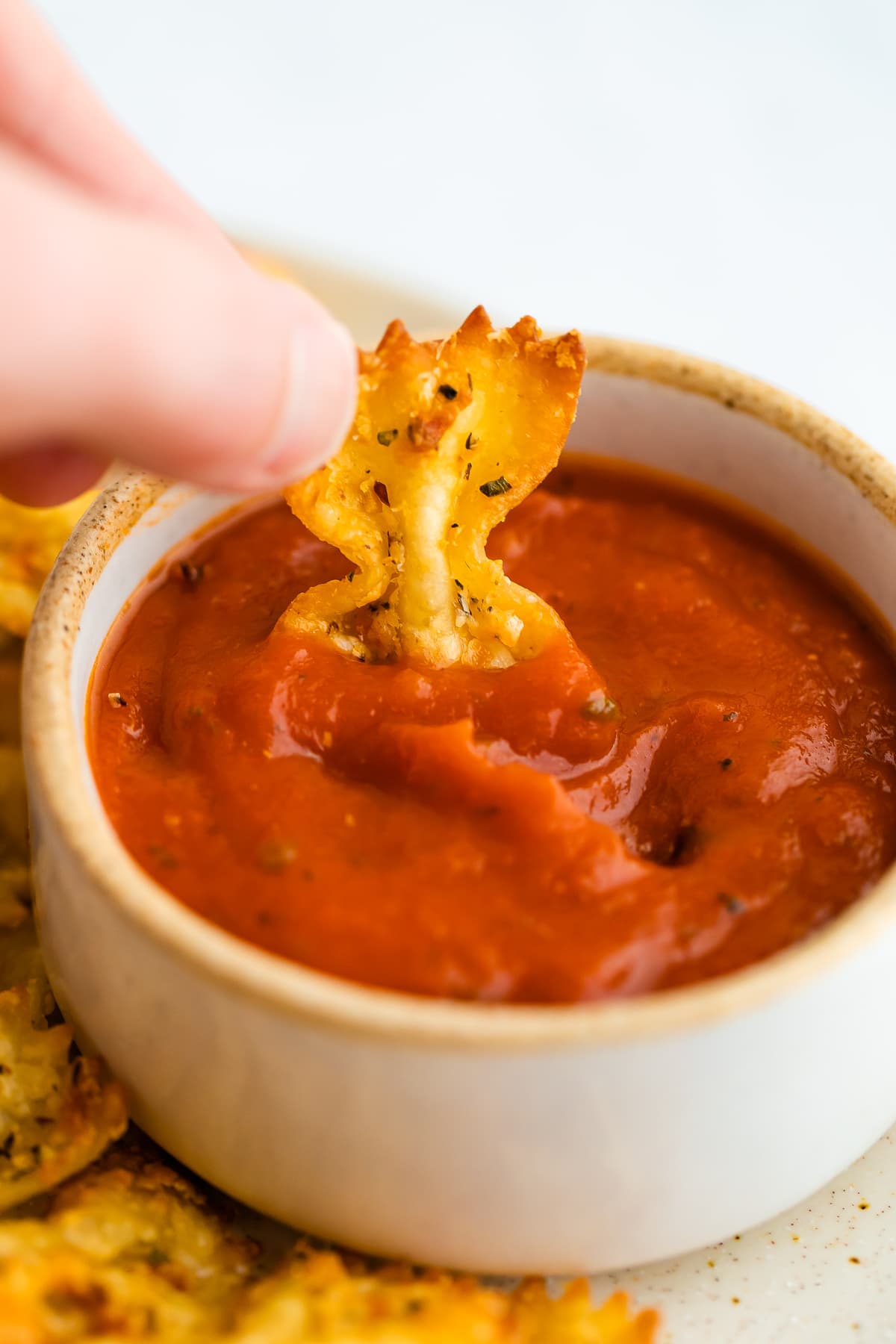 Dipping a pasta chip in to marinara sauce.