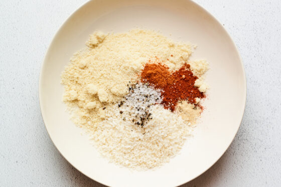 A large bowl with almond meal, coconut, paprika, cayenne, garlic, sea salt and black pepper ready to be combined.