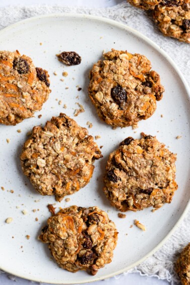 Five carrot cake breakfast cookies being served on a large white plate.