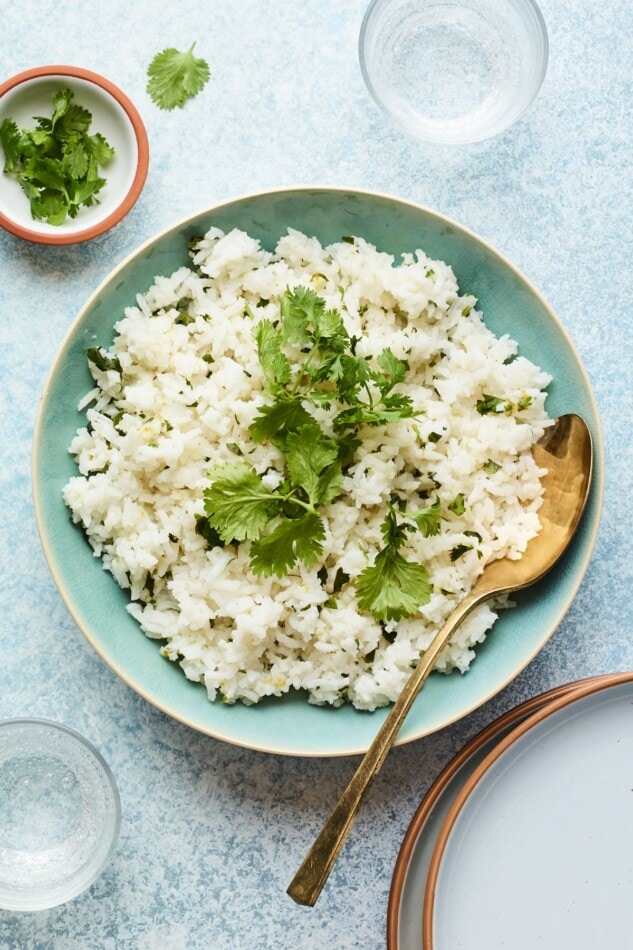 Overhead photo of a bowl of cilantro rice with a serving spoon.