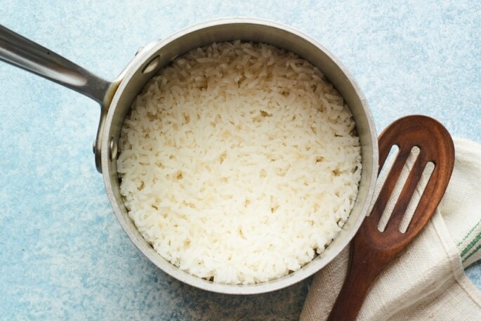 Overhead photo of cooked rice in a pot with a slated spoon.