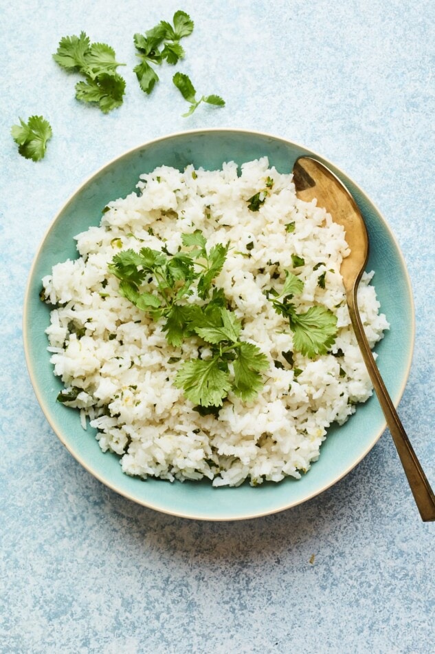 Overhead photo of easy cilantro rice in a serving bowl with a serving spoon.