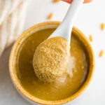 A hand spooning out some sunflower seed butter from a bowl.