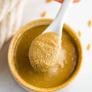 A hand spooning out some sunflower seed butter from a bowl.