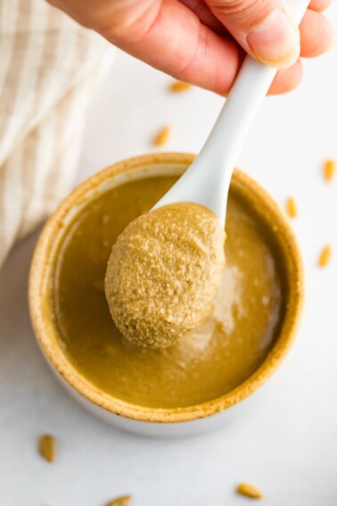 A hand spooning out some sunflower seed butter from a bowl.