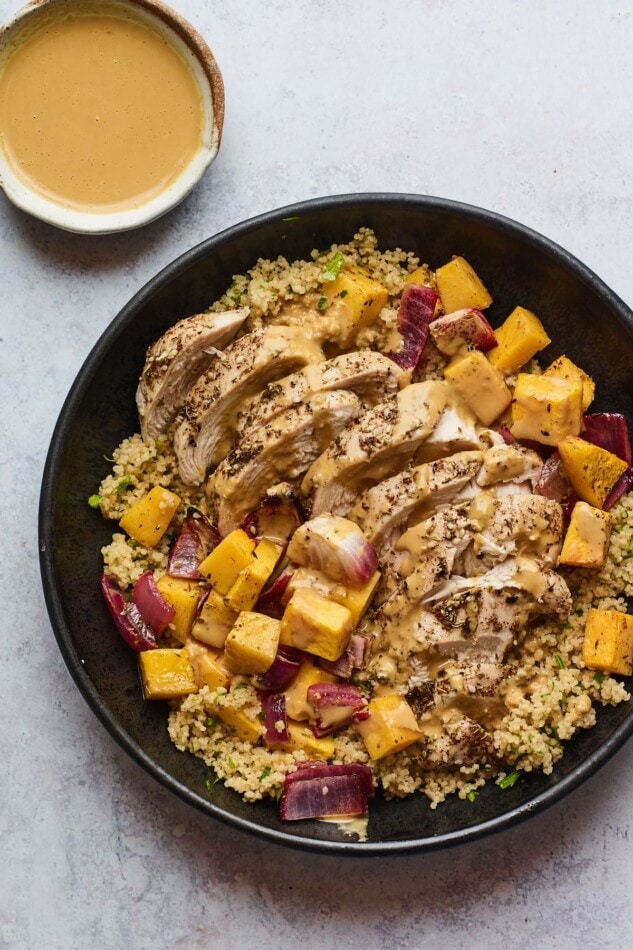 Za'atar Chicken with Butternut Squash and Red Onion A plate of Za'atar chicken and vegetables over a bed of herbed couscous.