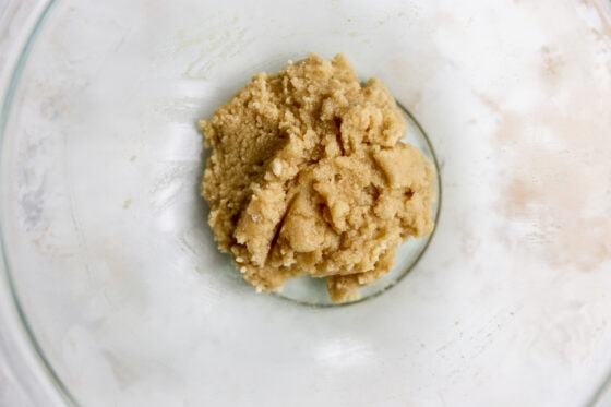 A cookie mixture in a large glass bowl that will be used to form a dough for homemade twix bars.