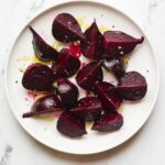 A serving of roasted beets on a large plate with drizzled olive oil.