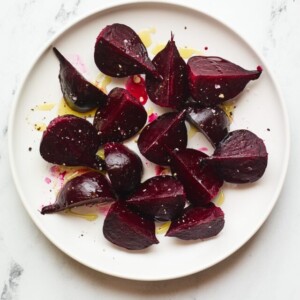 A serving of roasted beets on a large plate with drizzled olive oil.