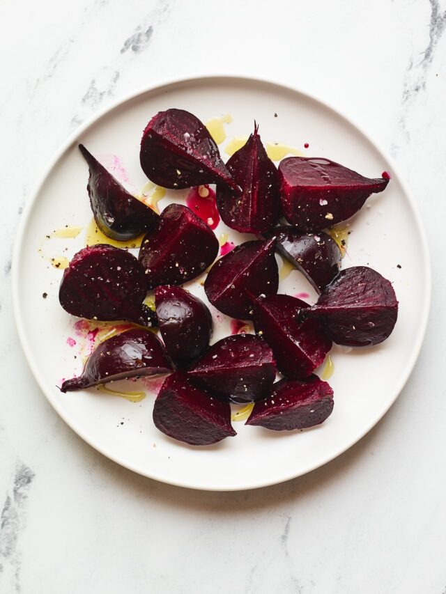 A serving of roasted beets on a large plate with drizzled olive oil.