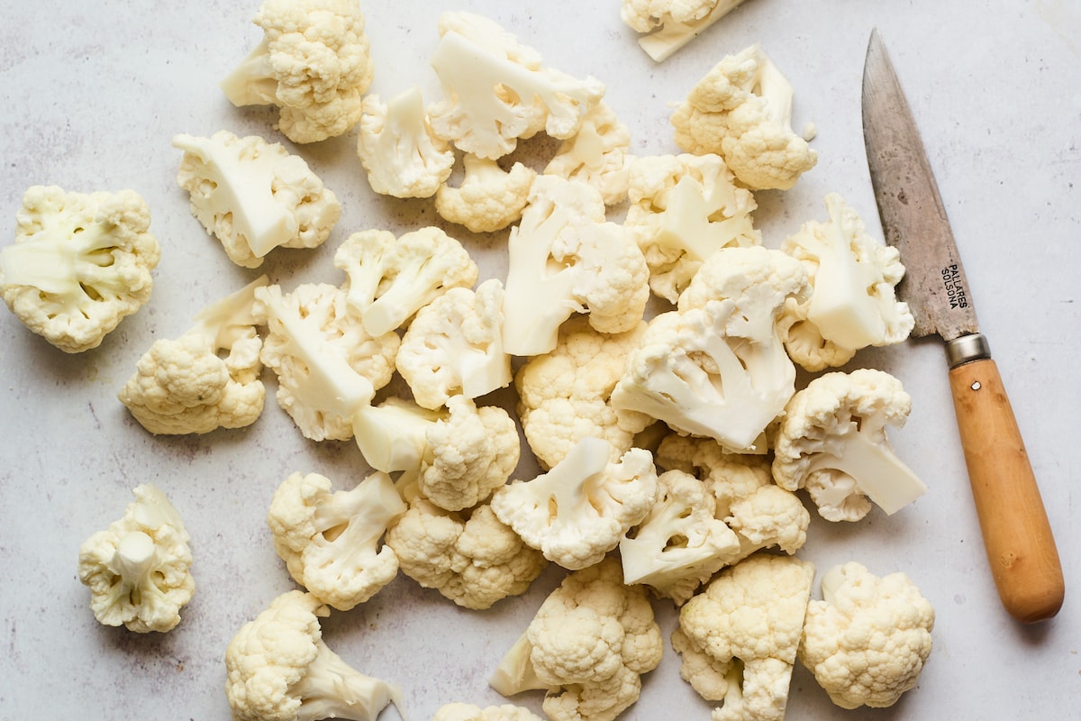 Chopped cauliflower florets with the knife used to chop them.