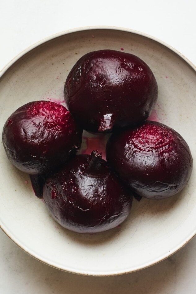 4 freshly roasted beets in a shallow bowl.