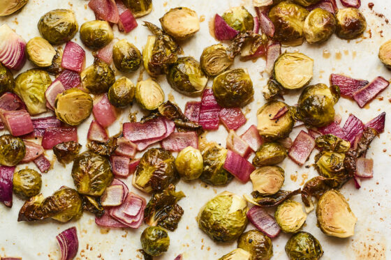 A sheet pan with freshly roasted roasted Brussels sprouts with red onion.