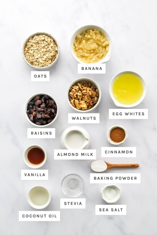 Baked Banana Oatmeal Cups Ingredients measured out to make banana baked oatmeal cups: oats, banana, egg whites, walnuts, raisins, almond milk, cinnamon, vanilla, baking powder, stevia, coconut oil and sea salt.