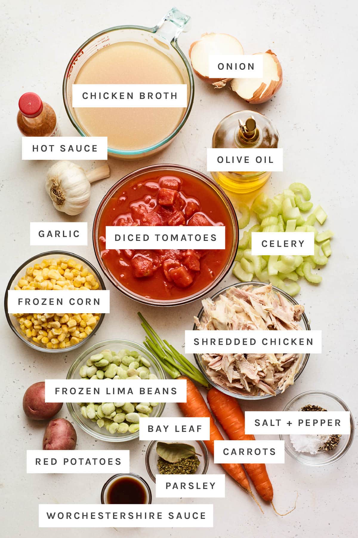 EASY & HEALTHY Brunswick Stew with Shredded Chicken Ingredients measured out to make Brunswick stew: chicken broth, onion, hot sauce, olive oil, garlic, diced tomatoes, celery, frozen corn, shredded chicken, frozen lima beans, red potatoes, bay leaf, salt and pepper, carrots, parsley and Worcestershire sauce.