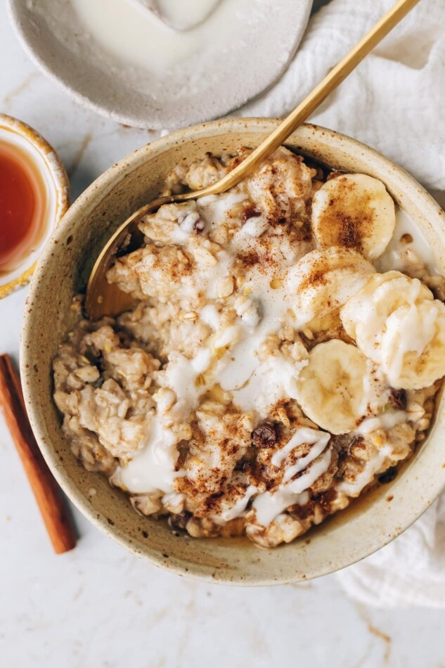 CINNAMON RAISIN OATMEAL // vegan & gluten-free An overhead photo of a bowl of cinnamon raisin oatmeal topped with banana slices and a drizzle of coconut butter.