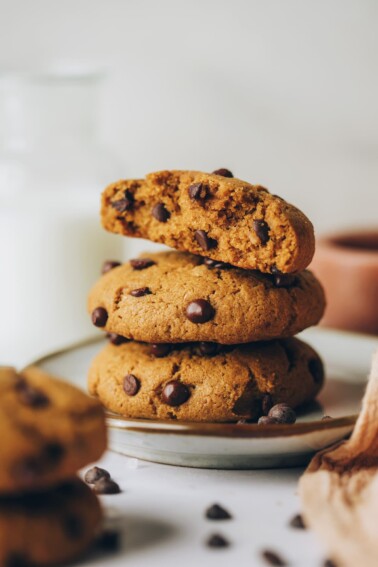 Three healthy chocolate chip cookies stacked on top of each other. The top cookie has been cut in half, exposing the inside.