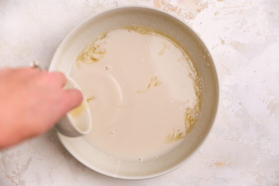 Almond milk and vinegar mixture added to a large mixing bowl.