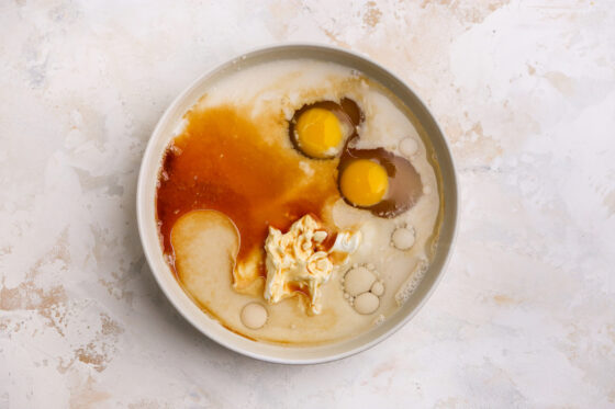Two eggs, maple syrup, Greek yogurt, coconut oil and vanilla extract added to the bowl with milk and vinegar.