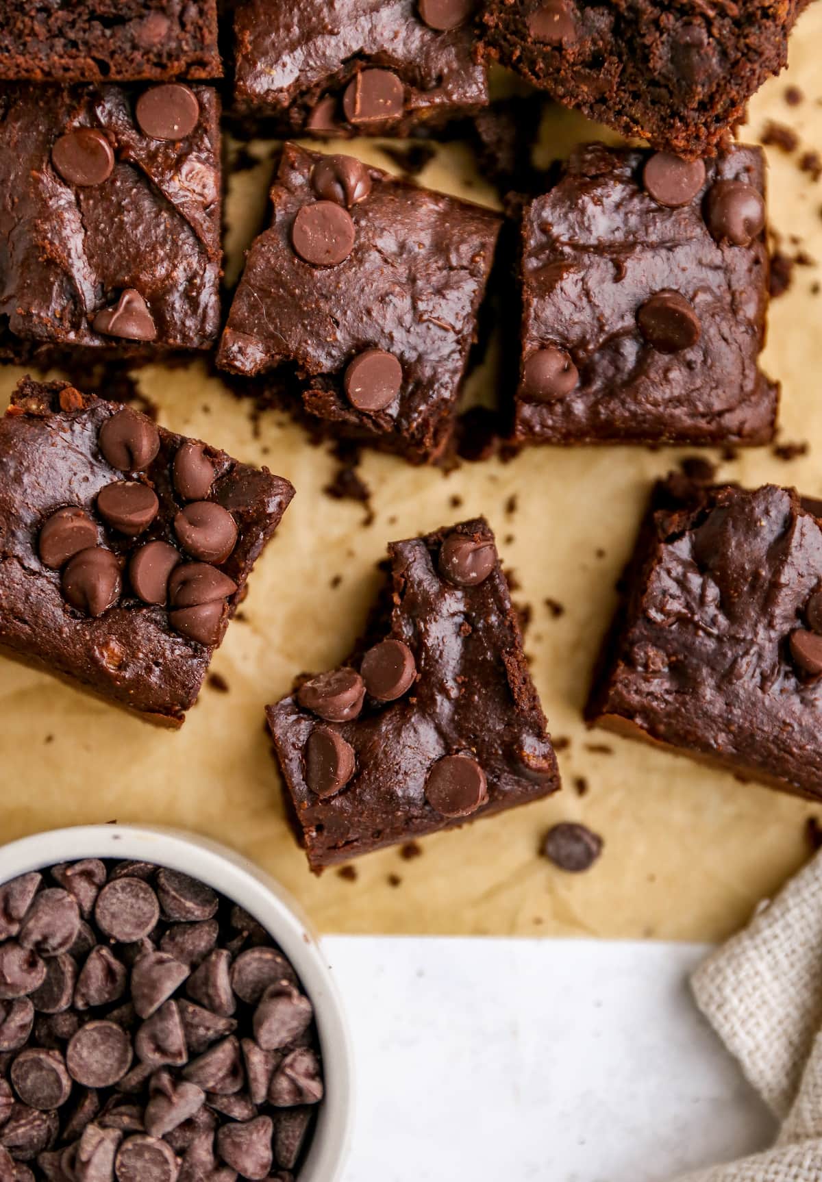 A sheet of brown parchment paper with protein brownie squares on top. The center brownie has a bite taken out of it.