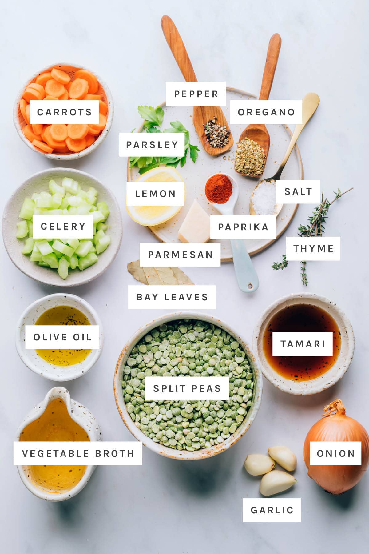 Ingredients measured out to make split pea soup: carrots, pepper, oregano, parsley, lemon, salt, paprika, parmesan, bay leaves, celery, olive oil, tamari, olive oil, split peas, vegetable broth, garlic and onion.
