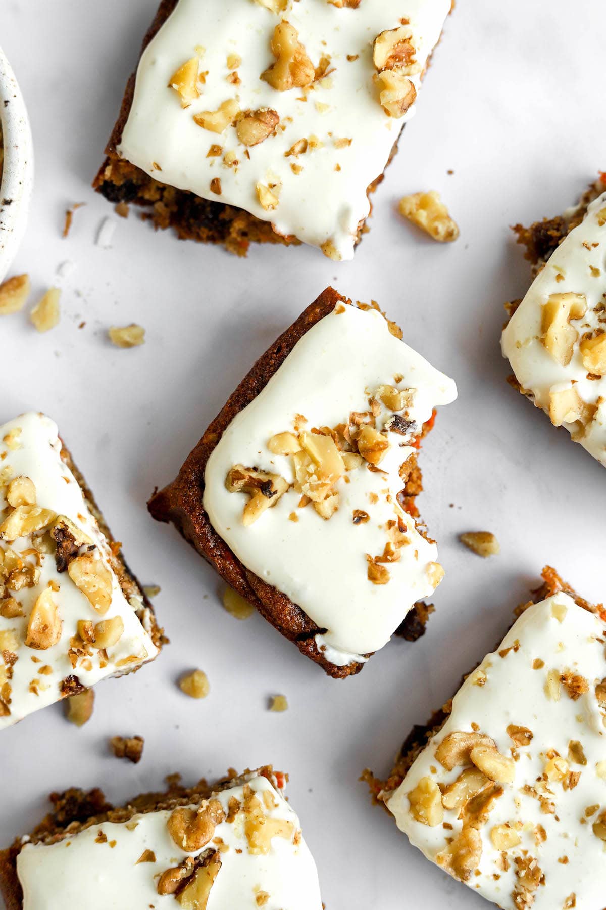 Lexi's Clean Kitchen Cookbook Several squares of carrot cake bars spread around. The center bar has a bite removed.